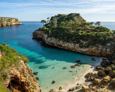 a beach with clear blue water next to cliff