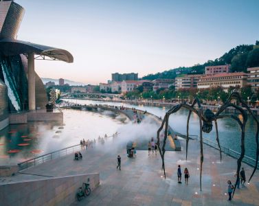 a large spider sculpture in front of a body of water