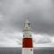 red and white lighthouse under a cloudy sky